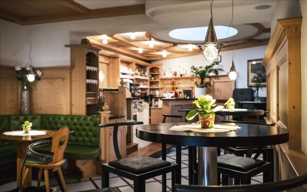 Area bar dell'hotel con arredi in legno e tavolini rotondi