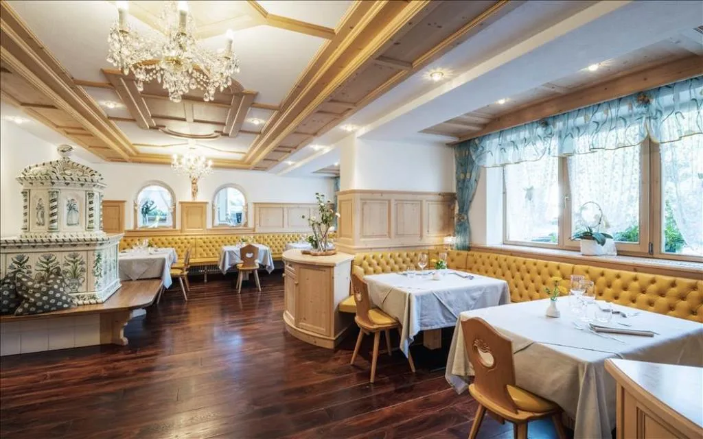 Sala ristorante elegante con stufa in maiolica, lampadario e panche gialle