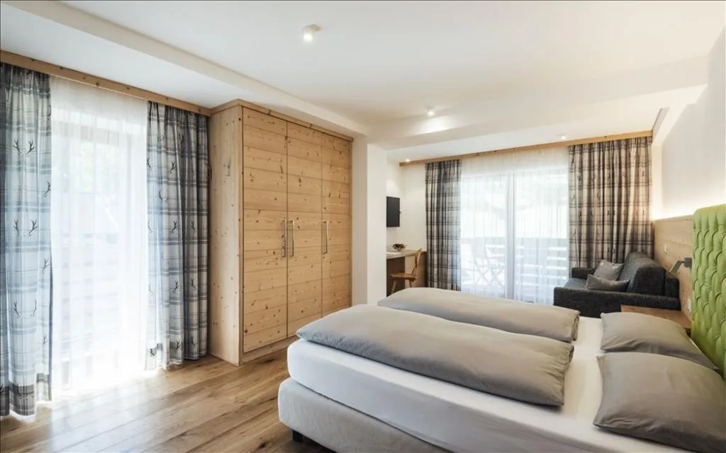 Camera luminosa con letto matrimoniale, armadio in legno e divano