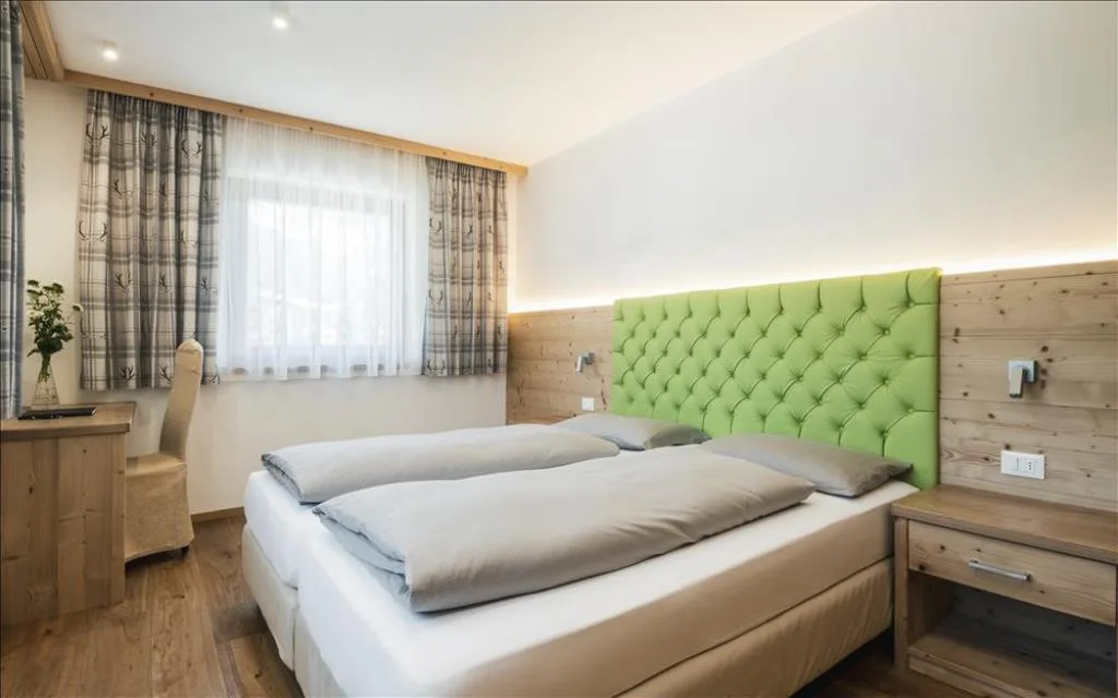 Camera con letto matrimoniale, testiera verde e scrivania in legno