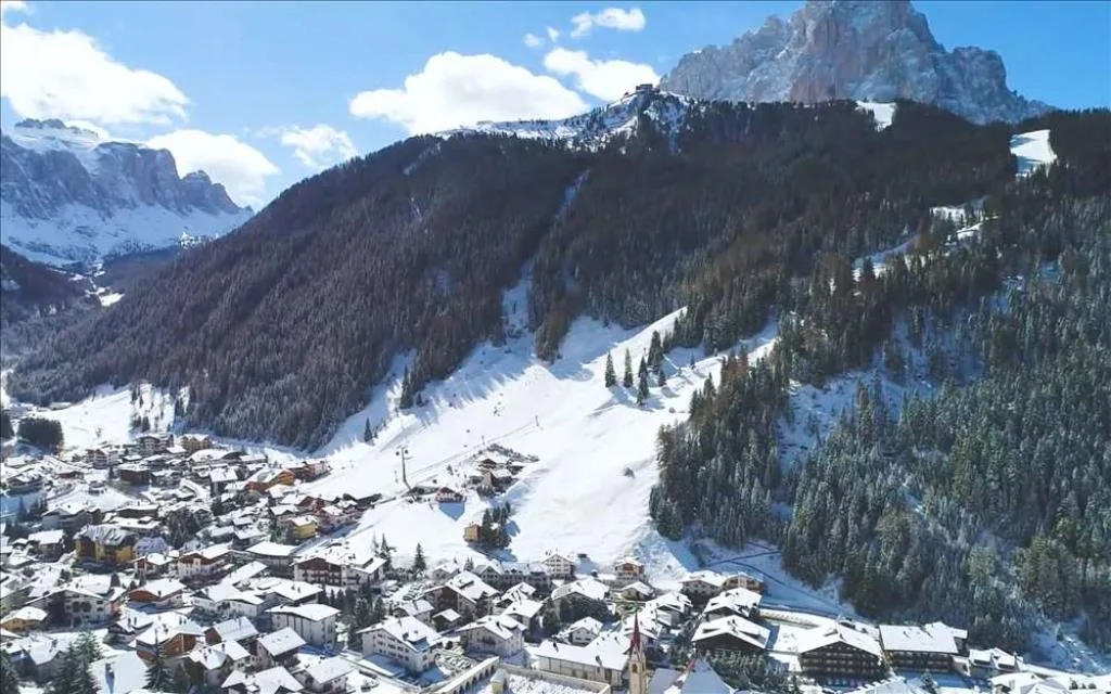 Panorama invernale del paese di montagna con case innevate e vette delle Dolomiti