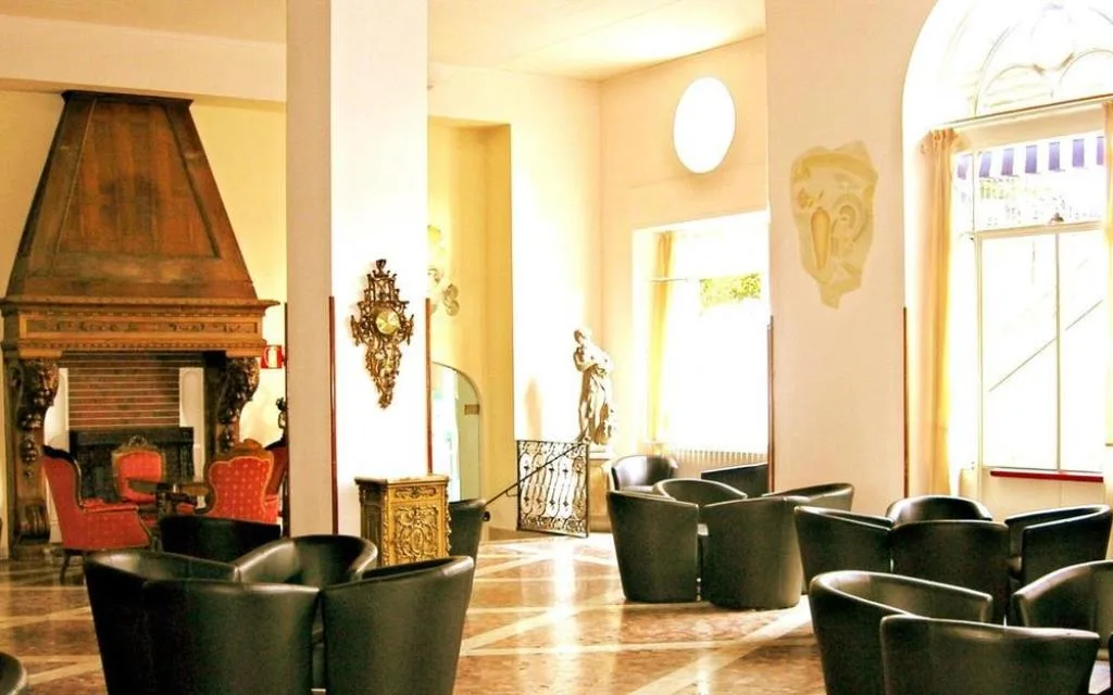 Hall dell'hotel con camino monumentale, poltrone in pelle e statue decorative