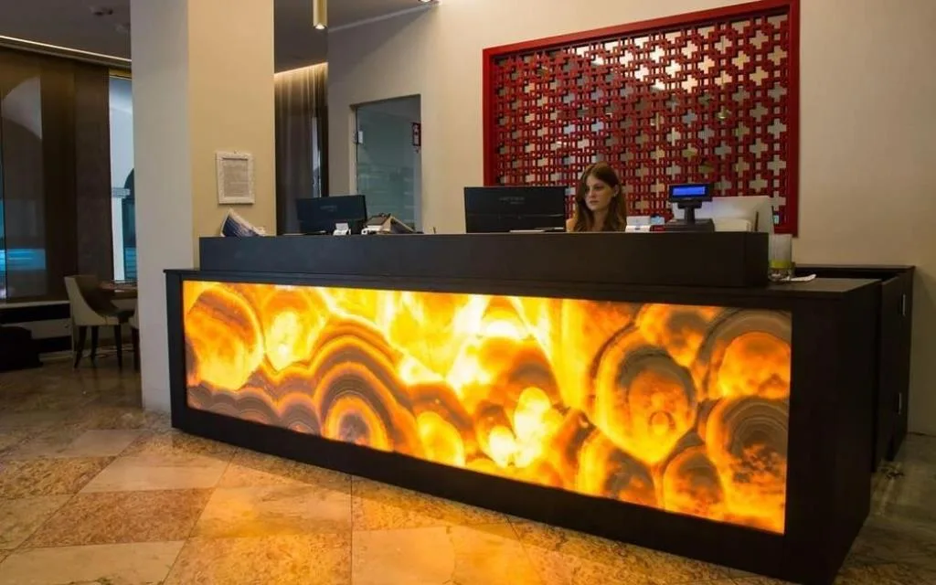 Reception moderna dell'hotel con bancone retroilluminato e receptionist