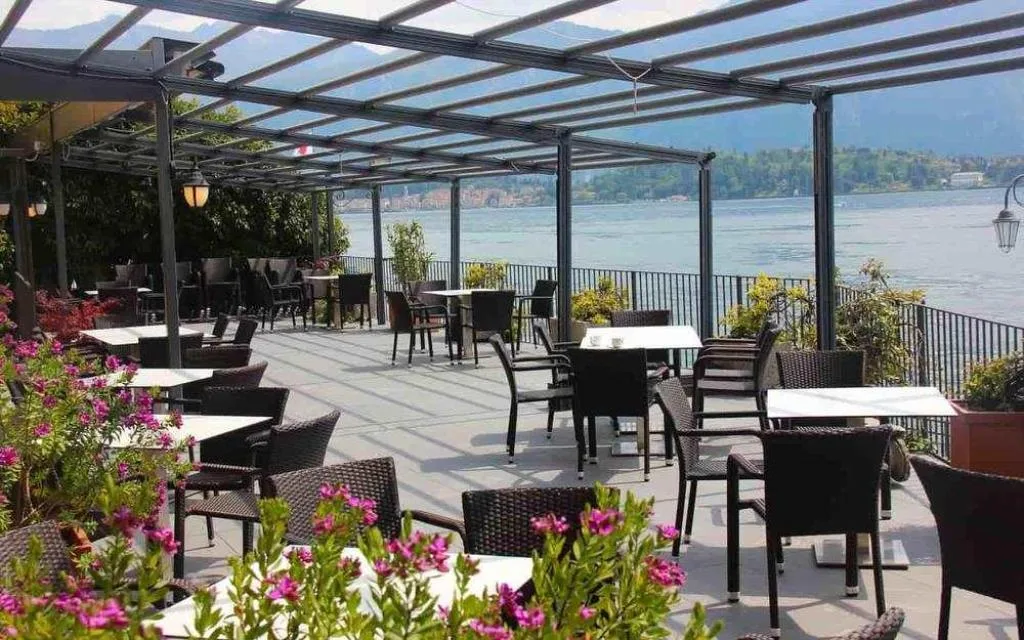 Terrazza ristorante con pergolato, tavoli e vista panoramica sul lago di Como