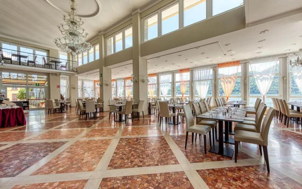 Ampia sala da pranzo con soffitti alti, lampadari, pavimento in marmo e grandi finestre