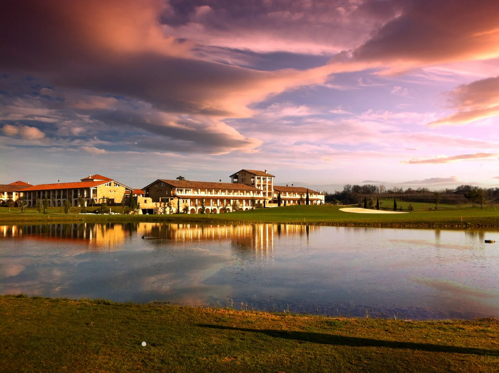 Veduta panoramica del resort al tramonto riflesso nel laghetto del campo da golf