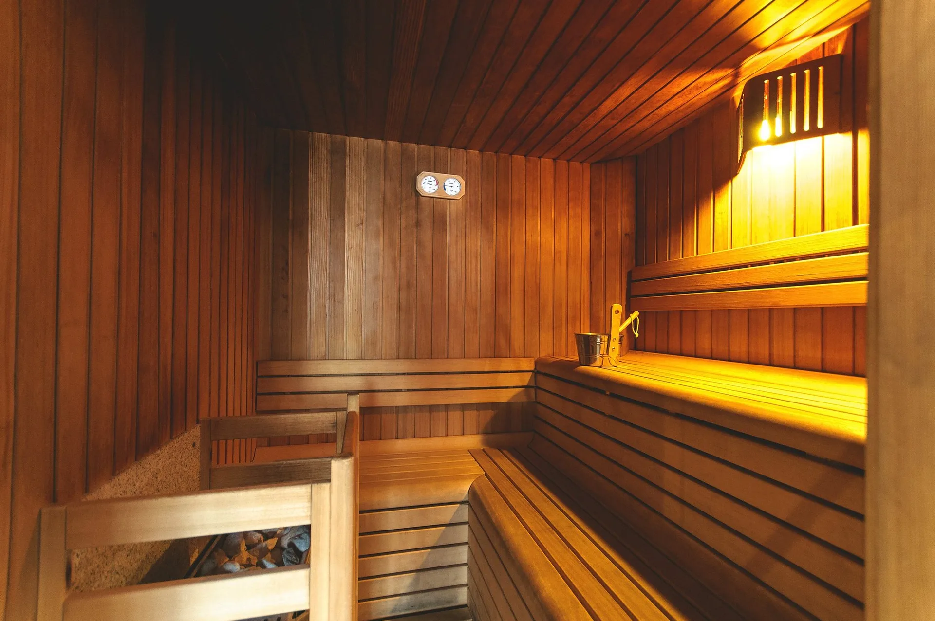 Sauna finlandese in legno con panche, illuminazione soffusa e secchio