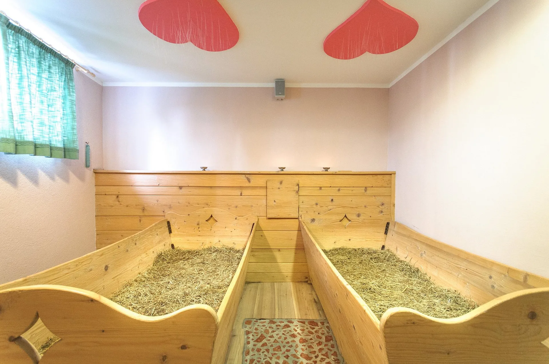 Bagno di fieno con lettini in legno riempiti di erba e decorazioni a forma di cuore