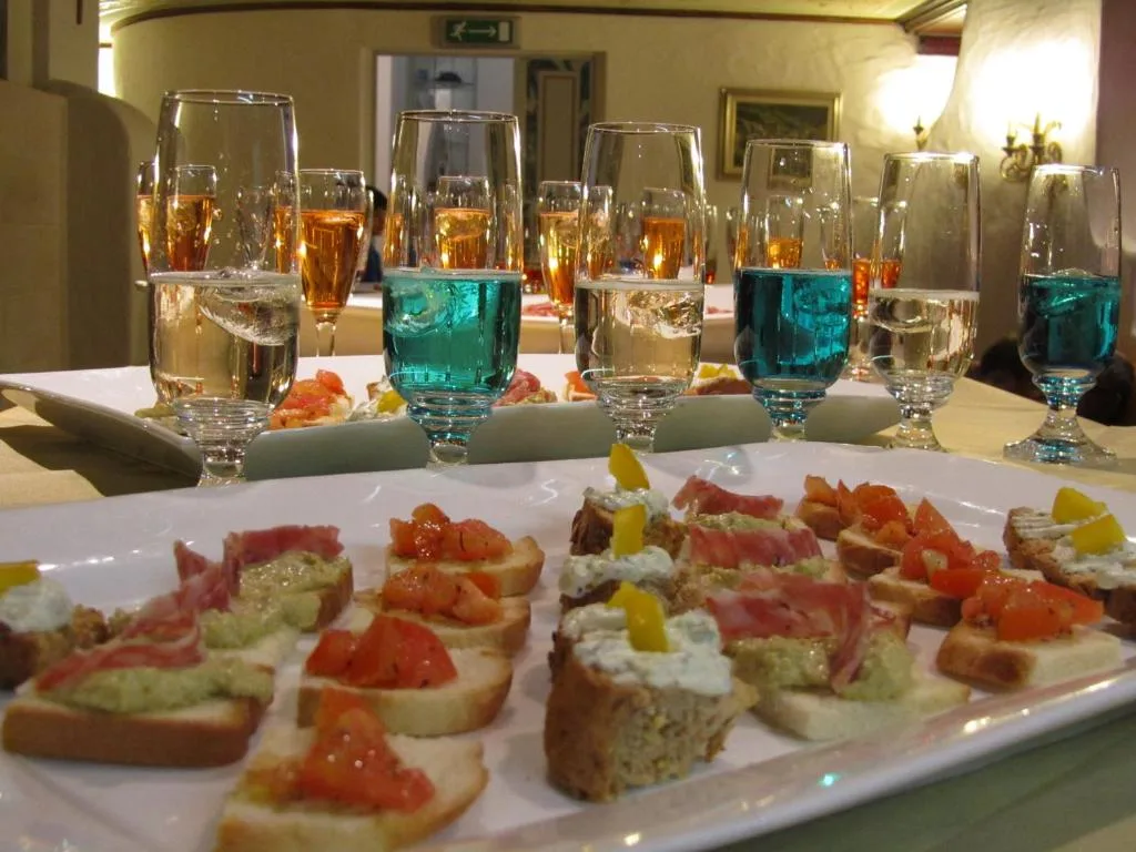 Aperitivo con tartine varie e bicchieri di bevande colorate su vassoi bianchi