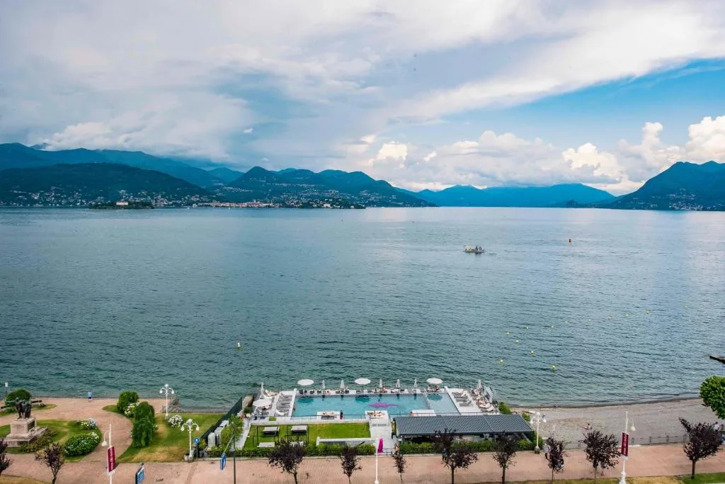 Veduta aerea del Lago Maggiore con piscina sul lungolago e le montagne sullo sfondo