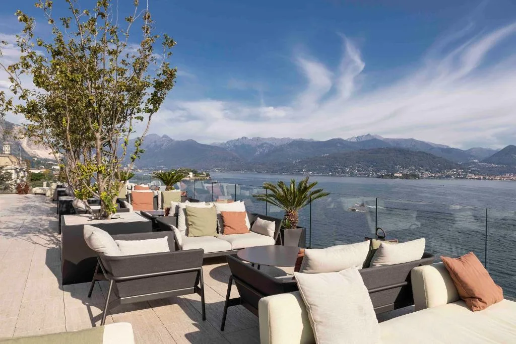 Terrazza lounge con divani, cuscini colorati e vista panoramica sul lago e le montagne