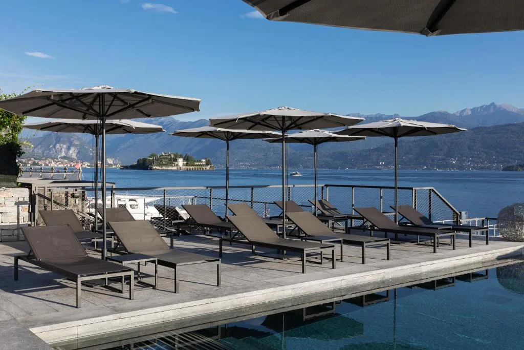Bordo piscina con lettini e ombrelloni e vista sull'Isola Bella e le montagne