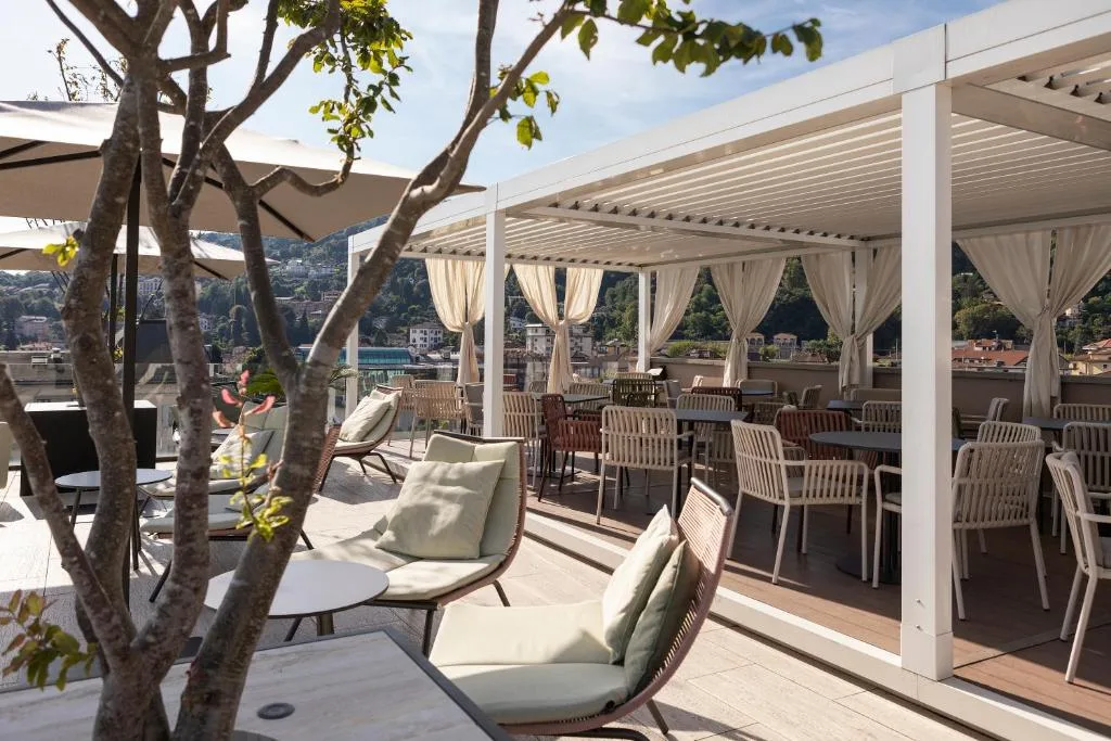 Terrazza rooftop con pergola bianca, divani e tavoli con vista sul paesaggio