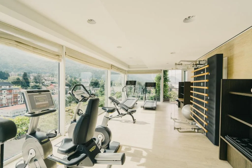 Palestra attrezzata con macchinari cardio e grandi vetrate con vista sulle montagne