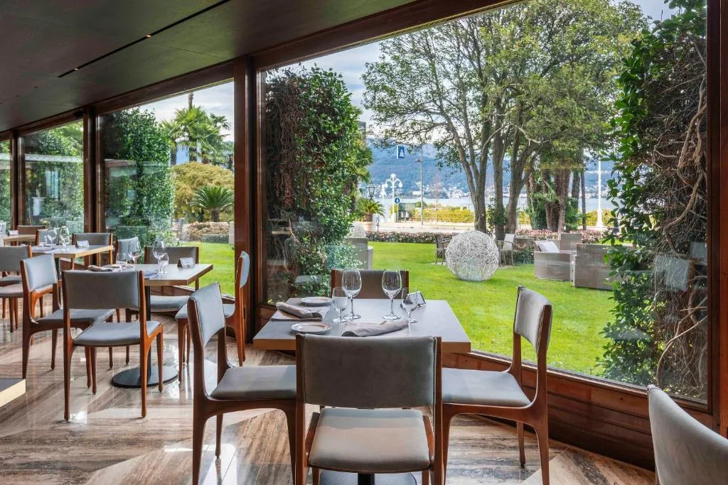 Sala ristorante interna con tavoli apparecchiati e ampie vetrate sul giardino