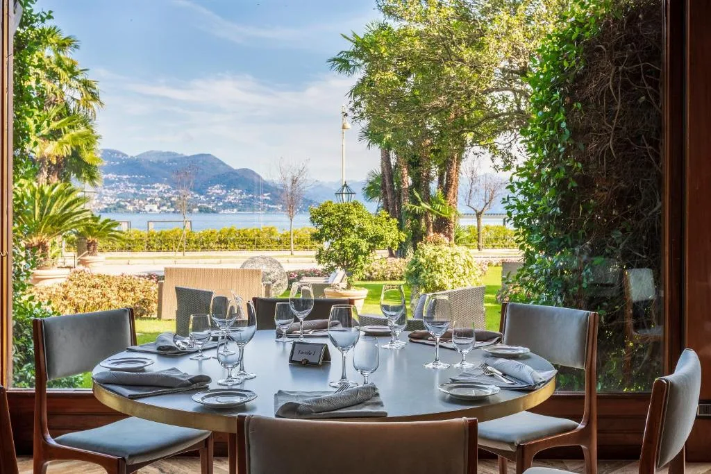 Tavolo rotondo apparecchiato con vista sul giardino, il lago e le montagne