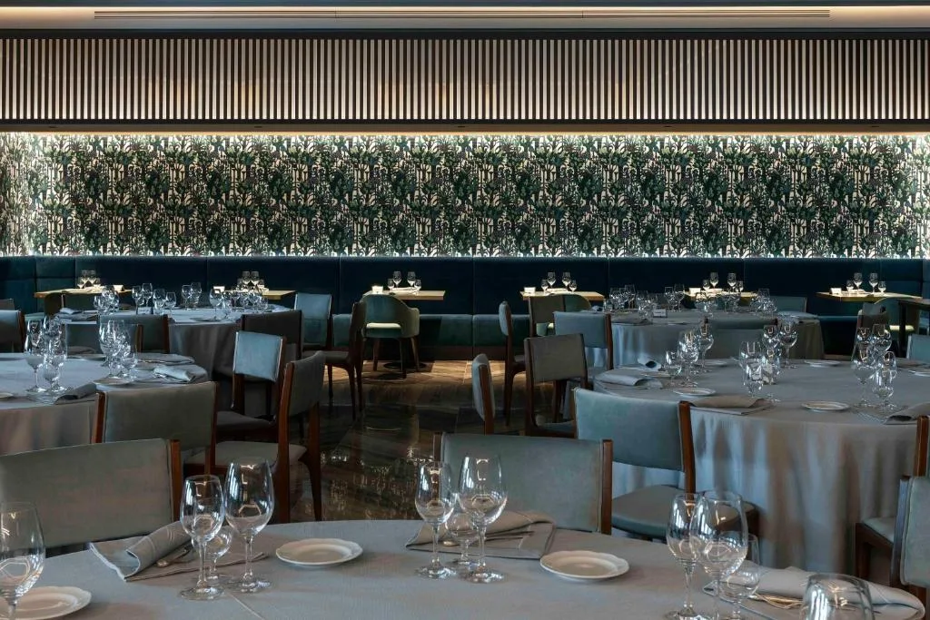 Sala ristorante raffinata con tavoli apparecchiati e parete decorata