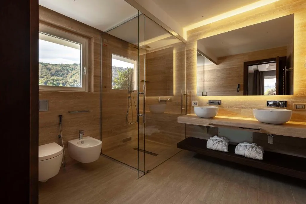 Bagno moderno con doppio lavabo, doccia in vetro e finestra con vista sul verde