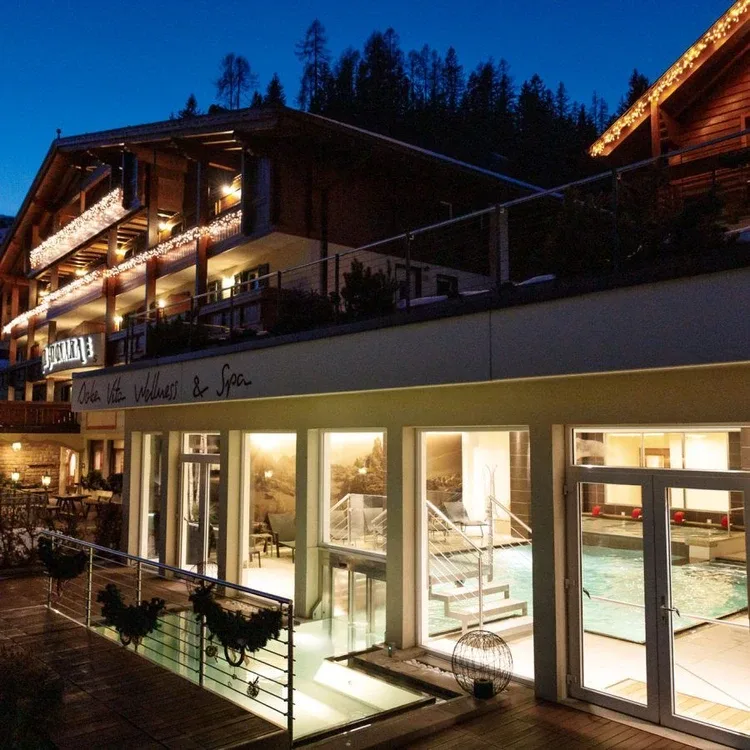Esterno dell'hotel di sera con luci e area wellness e spa illuminata