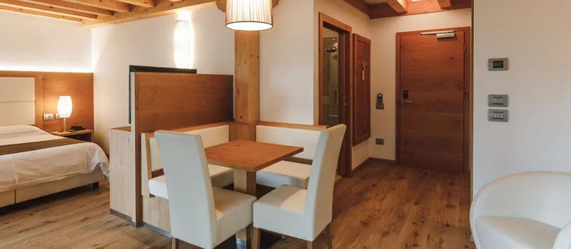 Camera con letto matrimoniale, tavolo da pranzo e arredi in legno