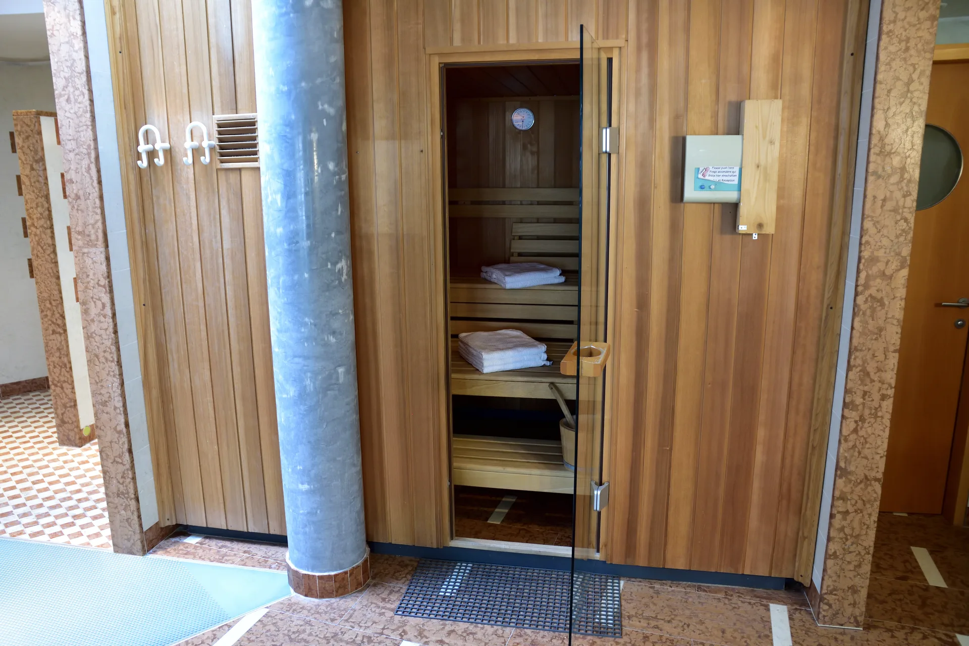 Sauna finlandese in legno con panche, asciugamani e area doccia adiacente