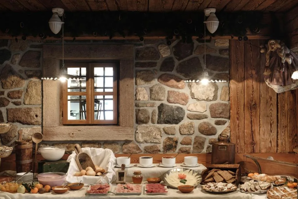 Buffet della colazione con salumi, formaggi e dolci in ambiente rustico in pietra