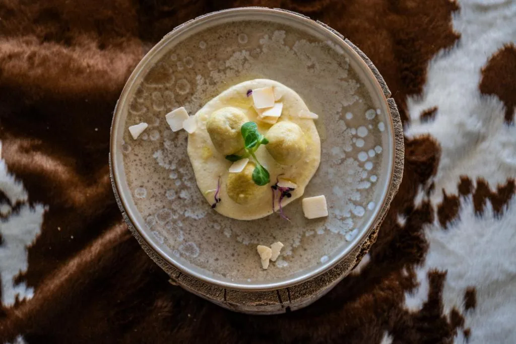 Canederli con crema di formaggio e scaglie su piatto raffinato
