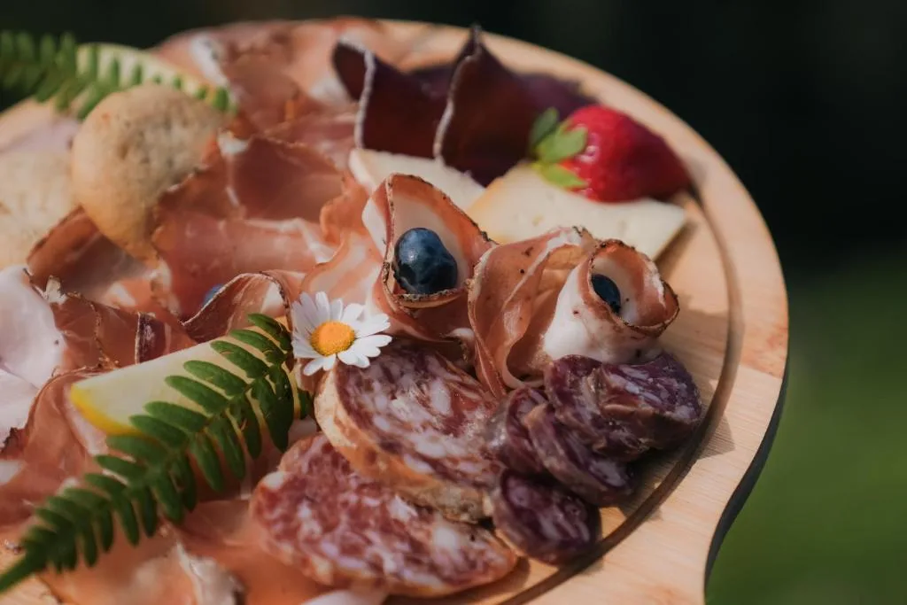 Tagliere di salumi misti decorato con frutta e fiori