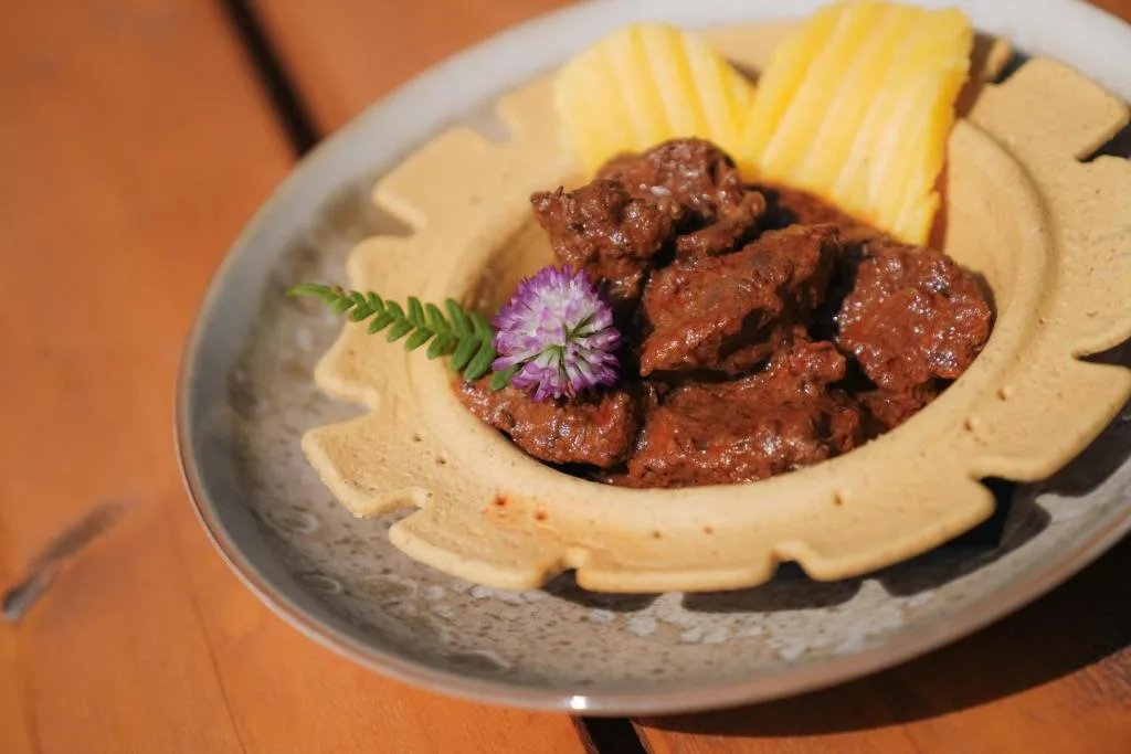 Spezzatino di carne con polenta gialla e fiore decorativo