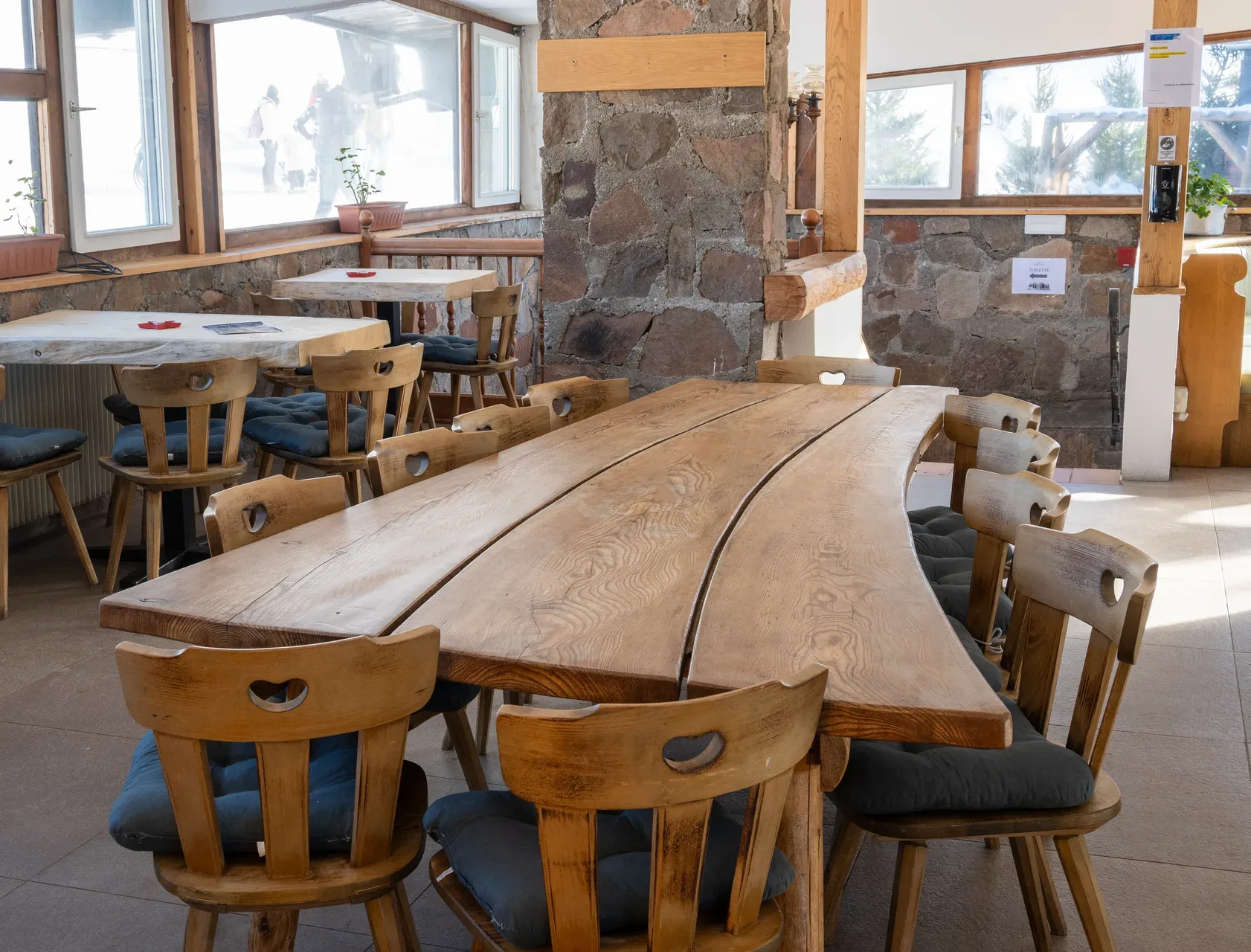 Sala interna rustica del ristorante con tavoli e sedie in legno