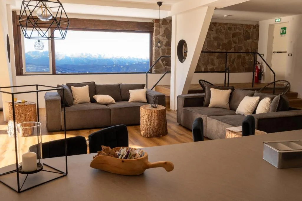 Area lounge con divani e vista panoramica sulle montagne dalla grande finestra