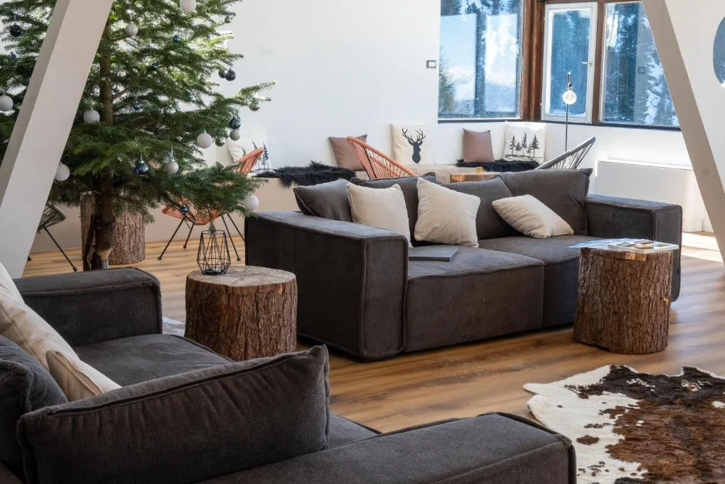 Salotto accogliente con divani, albero di Natale e tavolini in tronco d'albero