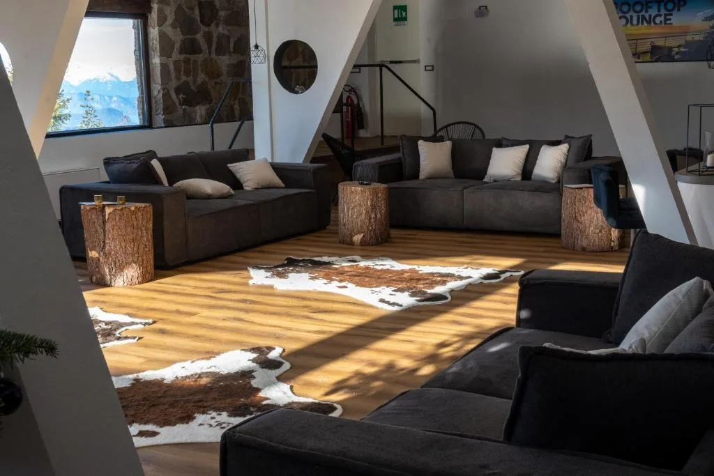 Lounge moderna con divani grigi, tappeti in pelle e vista sulle montagne