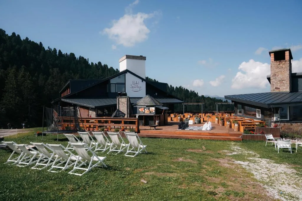 Vista estiva dell'Hotel Sporting con prato verde, sdraio e terrazza
