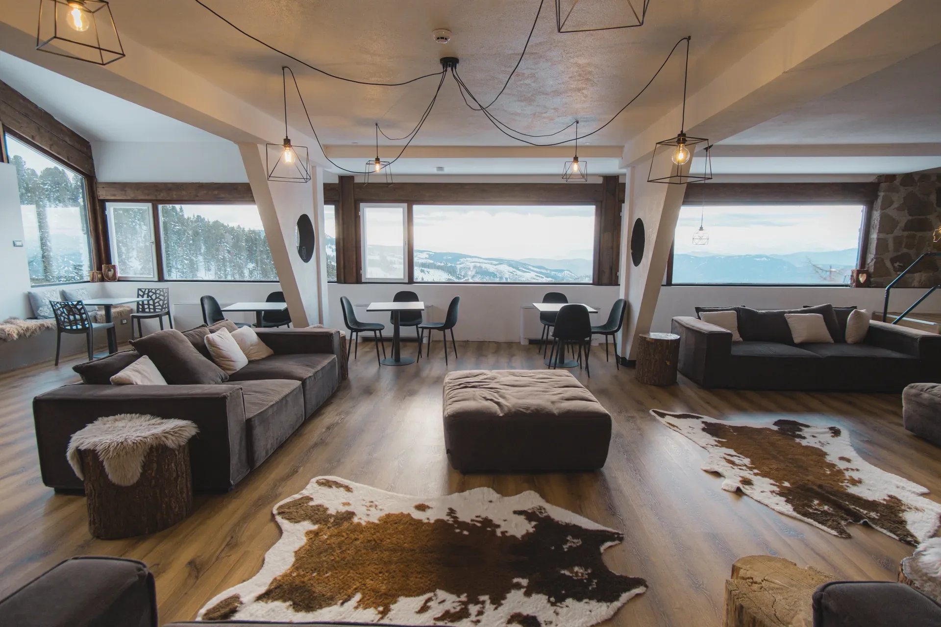 Ampia lounge panoramica con divani, tappeti in pelle e vista sulle montagne innevate
