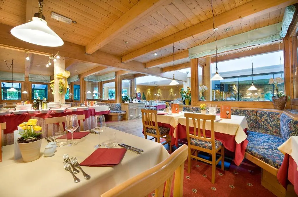 Sala ristorante rustica con soffitto in legno, tavoli apparecchiati e tovaglie rosse