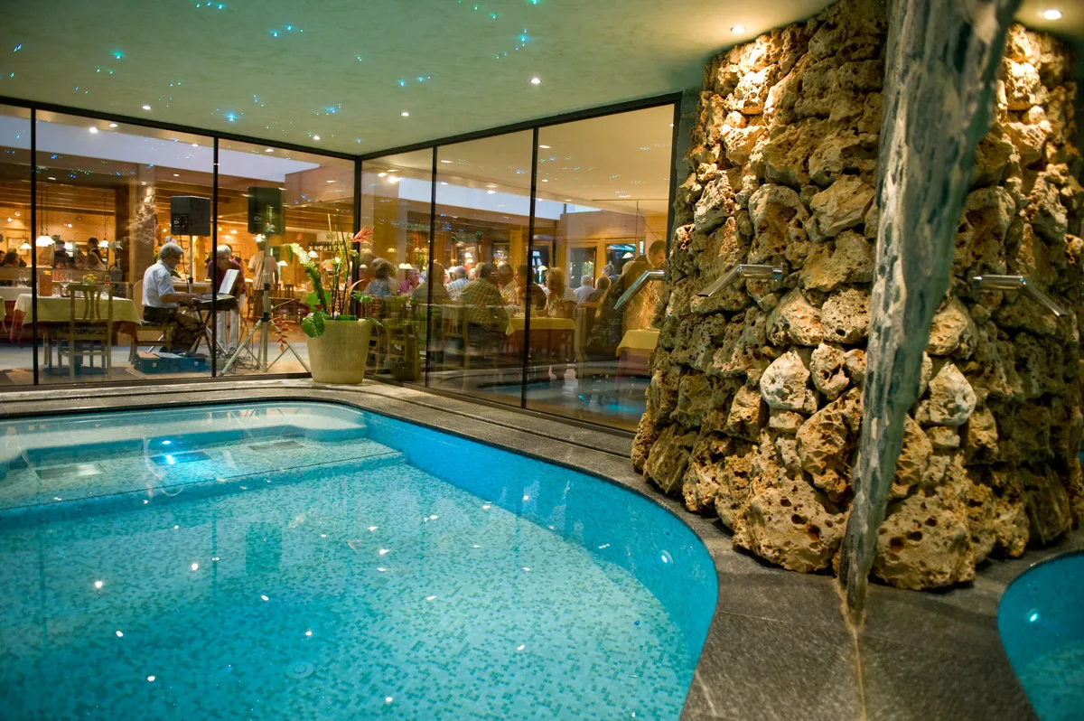 Piscina coperta con parete in pietra e vista sul ristorante attraverso le vetrate