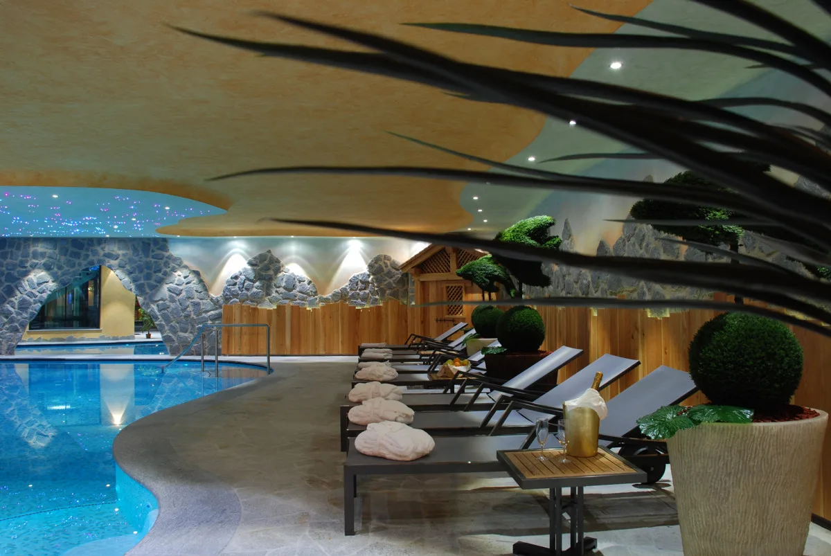 Area benessere con piscina interna, lettini e ambientazione a tema montagna