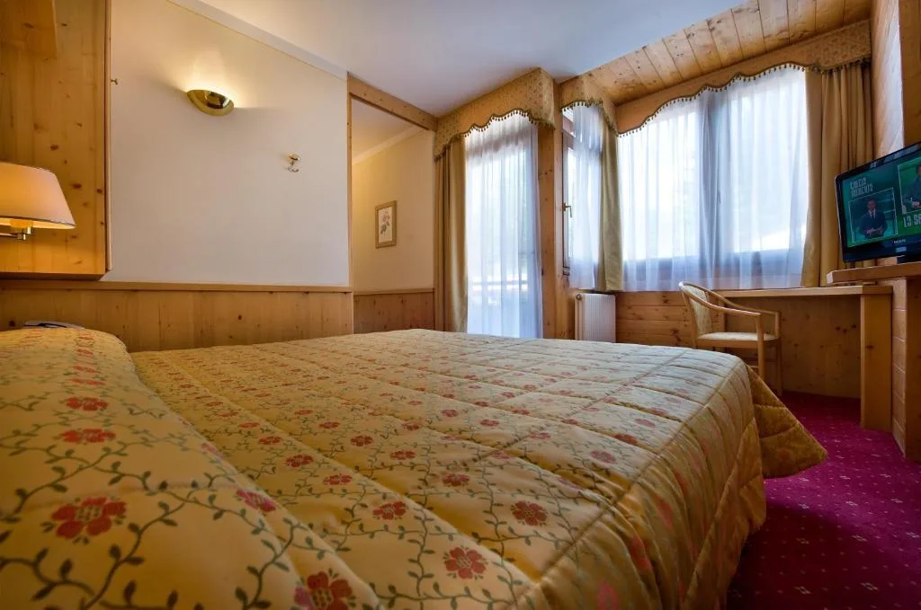 Camera matrimoniale in stile alpino con pareti in legno e copriletto floreale