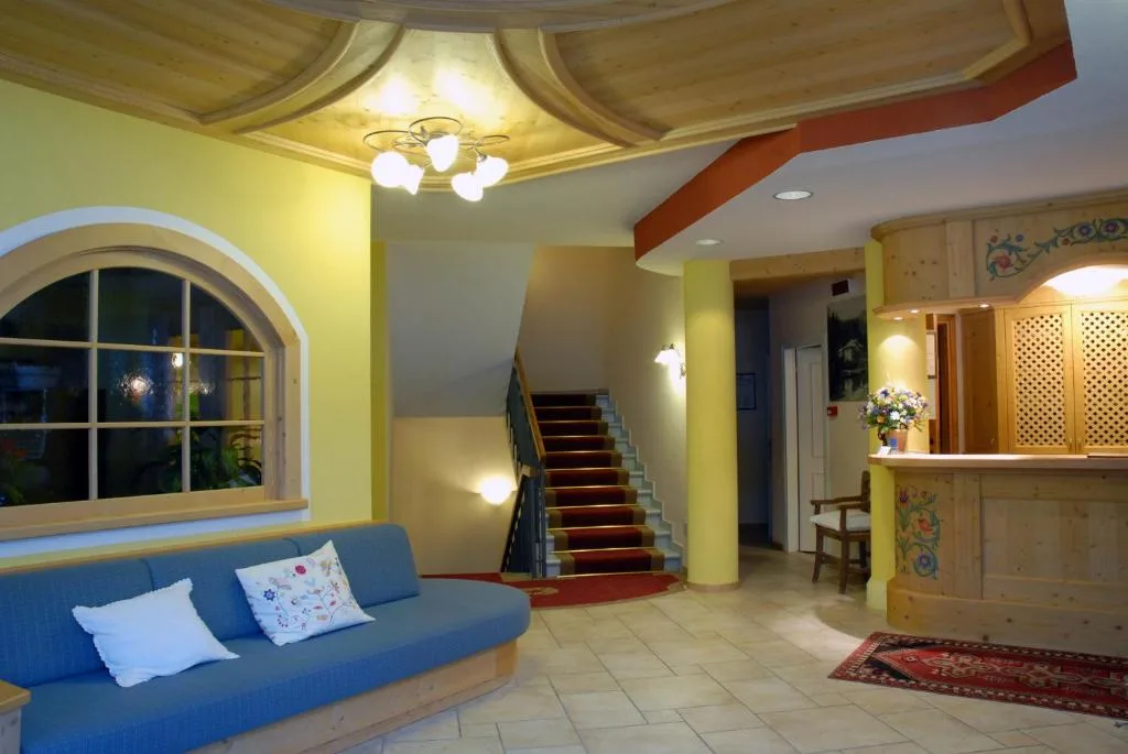 Hall dell'hotel con divano blu, reception in legno decorato e scala interna