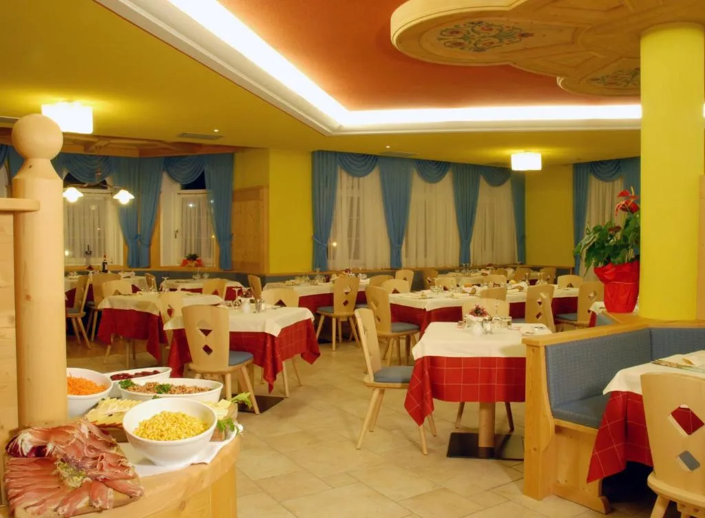 Sala ristorante con buffet in primo piano e tavoli apparecchiati