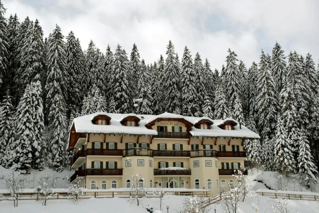 Facciata dell'hotel in inverno con neve sul tetto e abeti innevati