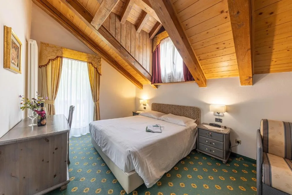 Camera mansardata con letto matrimoniale, soffitto in legno e moquette verde
