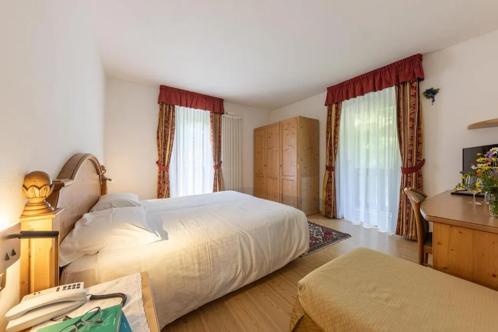 Camera luminosa con letto matrimoniale, armadio in legno e due finestre