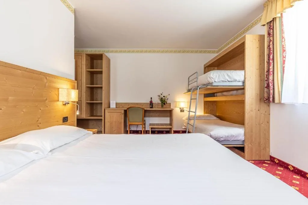 Camera con letto matrimoniale, letti a castello e arredi in legno chiaro