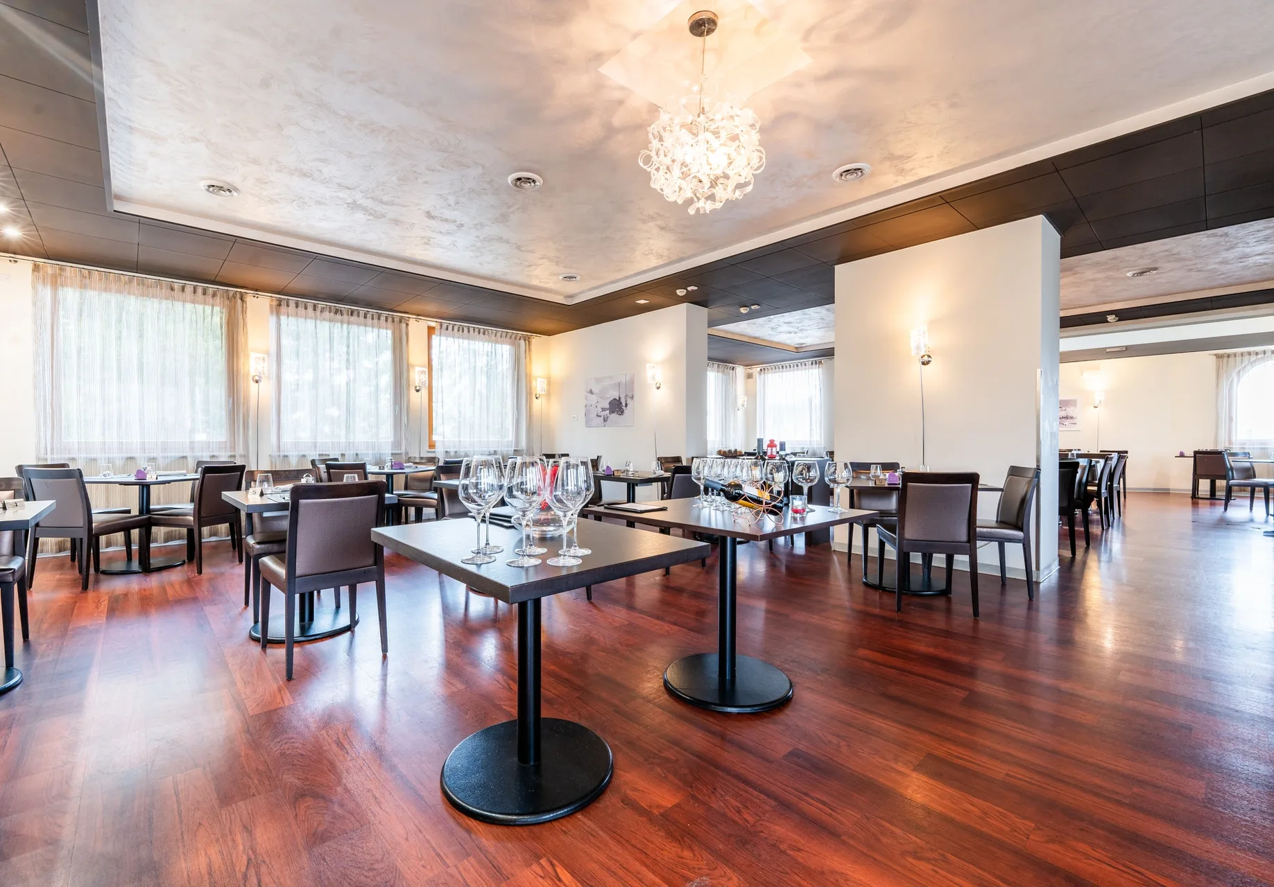 Sala ristorante luminosa con tavoli apparecchiati e grandi finestre