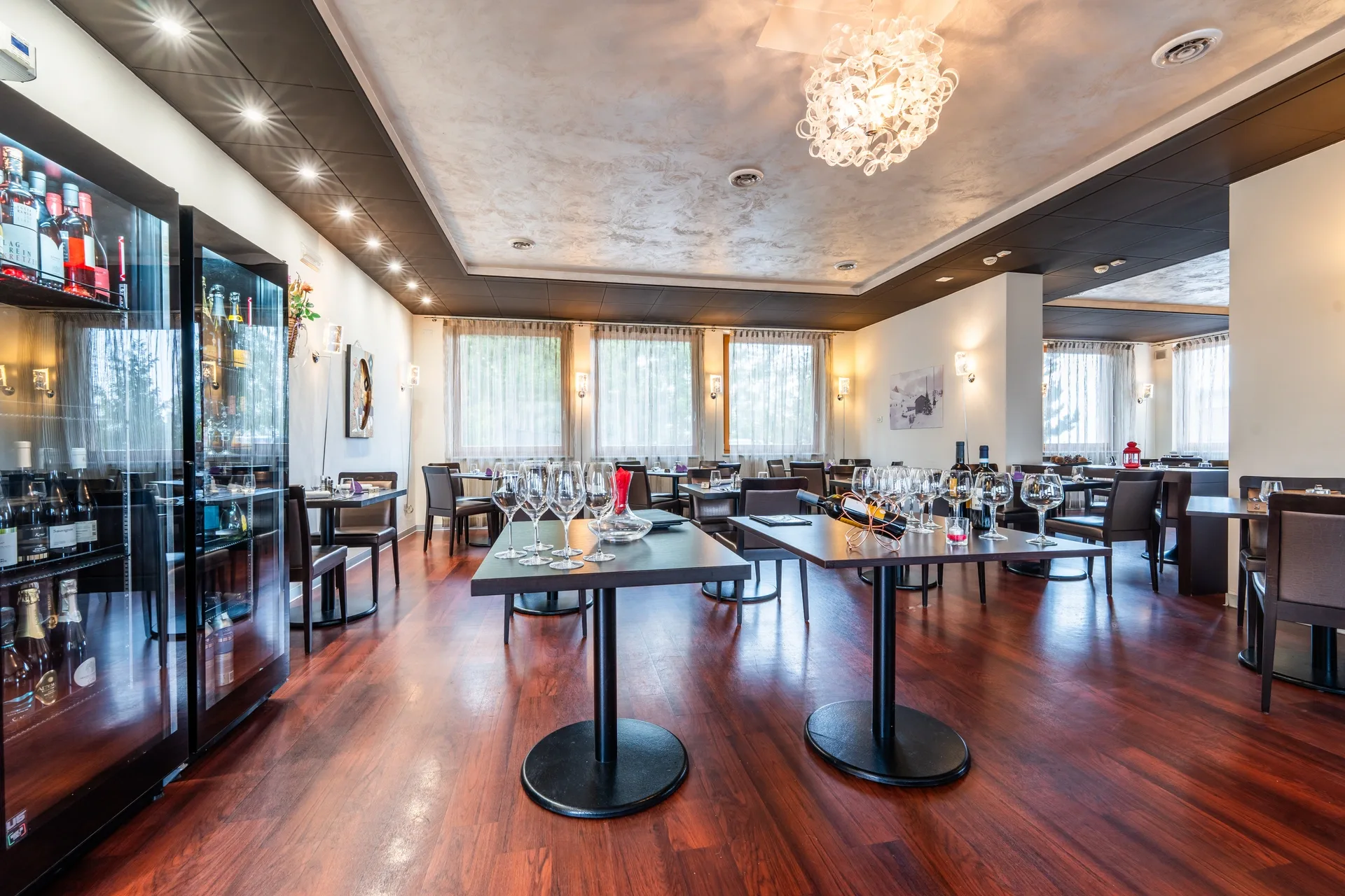 Sala ristorante con frigo vini e tavoli con calici disposti