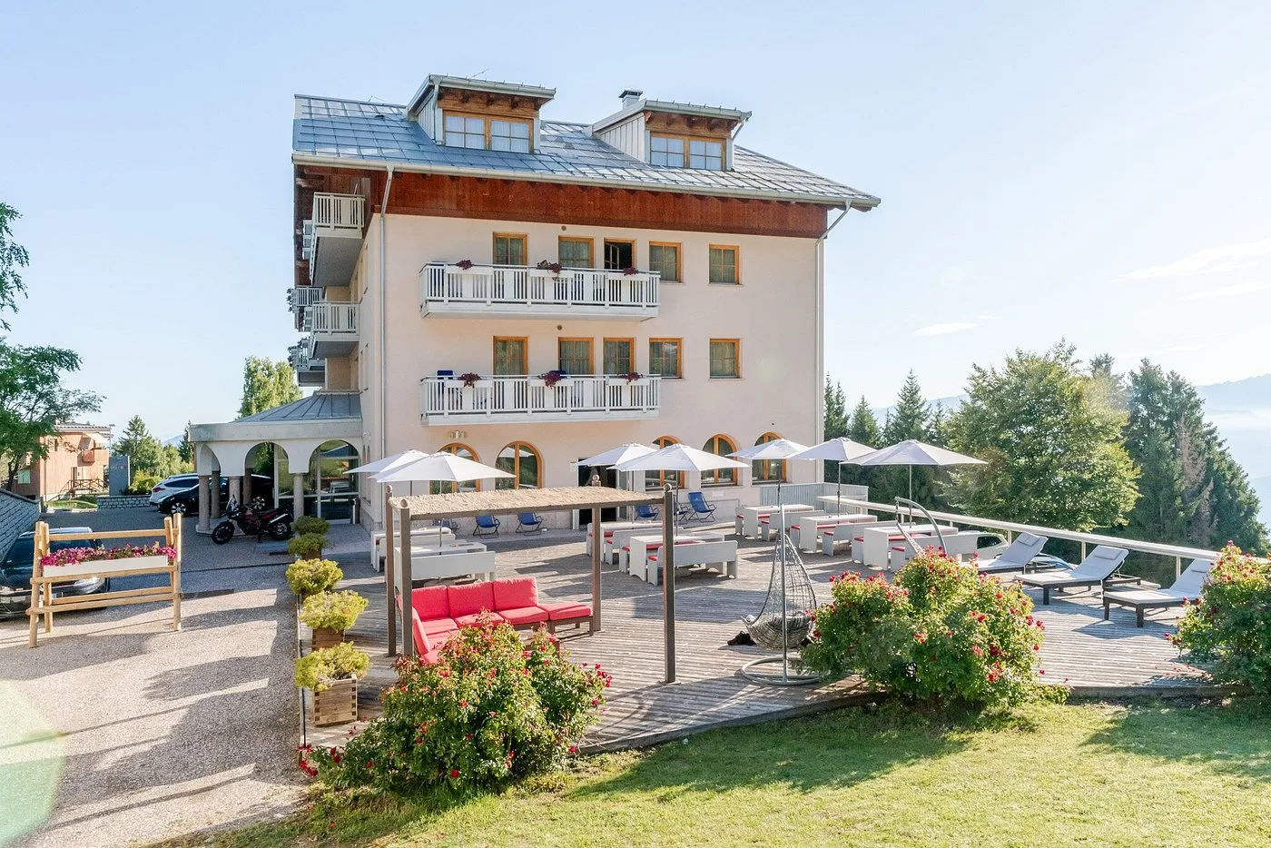 Esterno dell'hotel in estate con terrazza, ombrelloni e prato verde