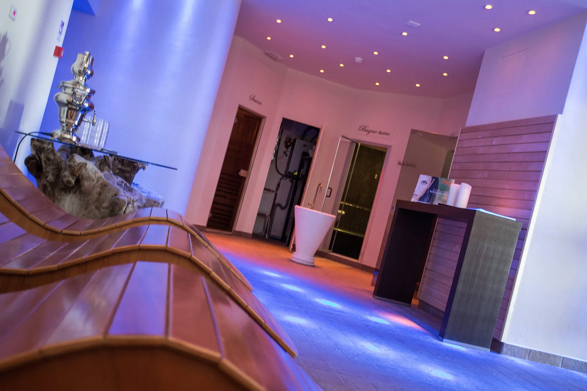Zona relax della spa con lettini in legno e luci colorate