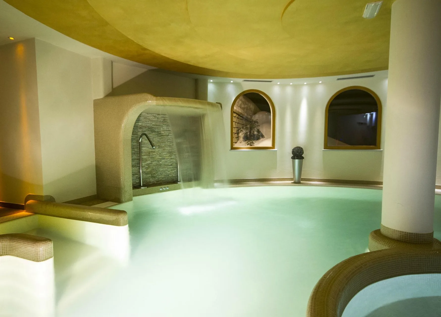 Piscina interna con cascata d'acqua e finestre ad arco